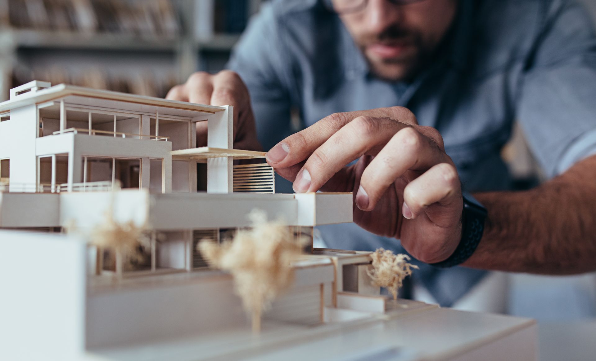Une personne disposant une petite maquette architecturale d'une maison moderne sur une table.