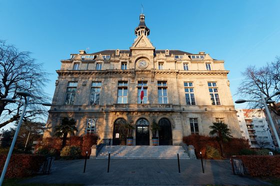 Bâtiment historique en pierre, à la façade ornée et à la tour centrale, vu de face au coucher du soleil.