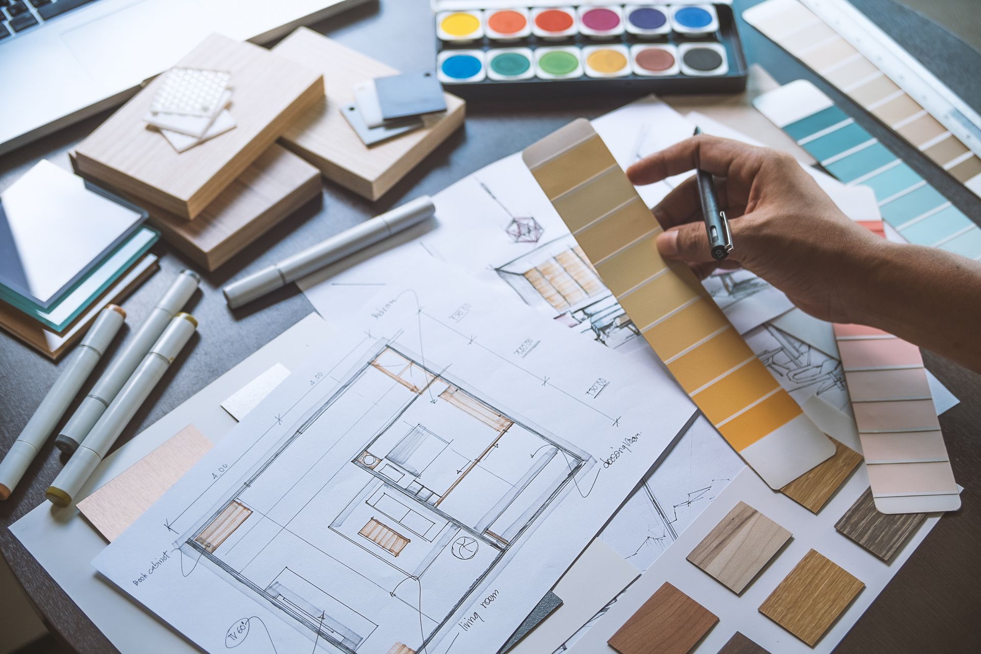 Un designer dispose des échantillons de couleurs et des croquis de plans d'étage sur un bureau.