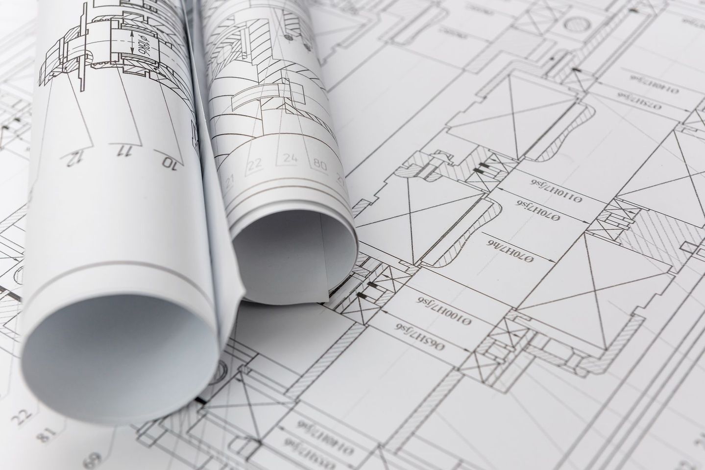 Plans architecturaux enroulés sur un dessin technique avec des croquis de plans d'étage visibles.