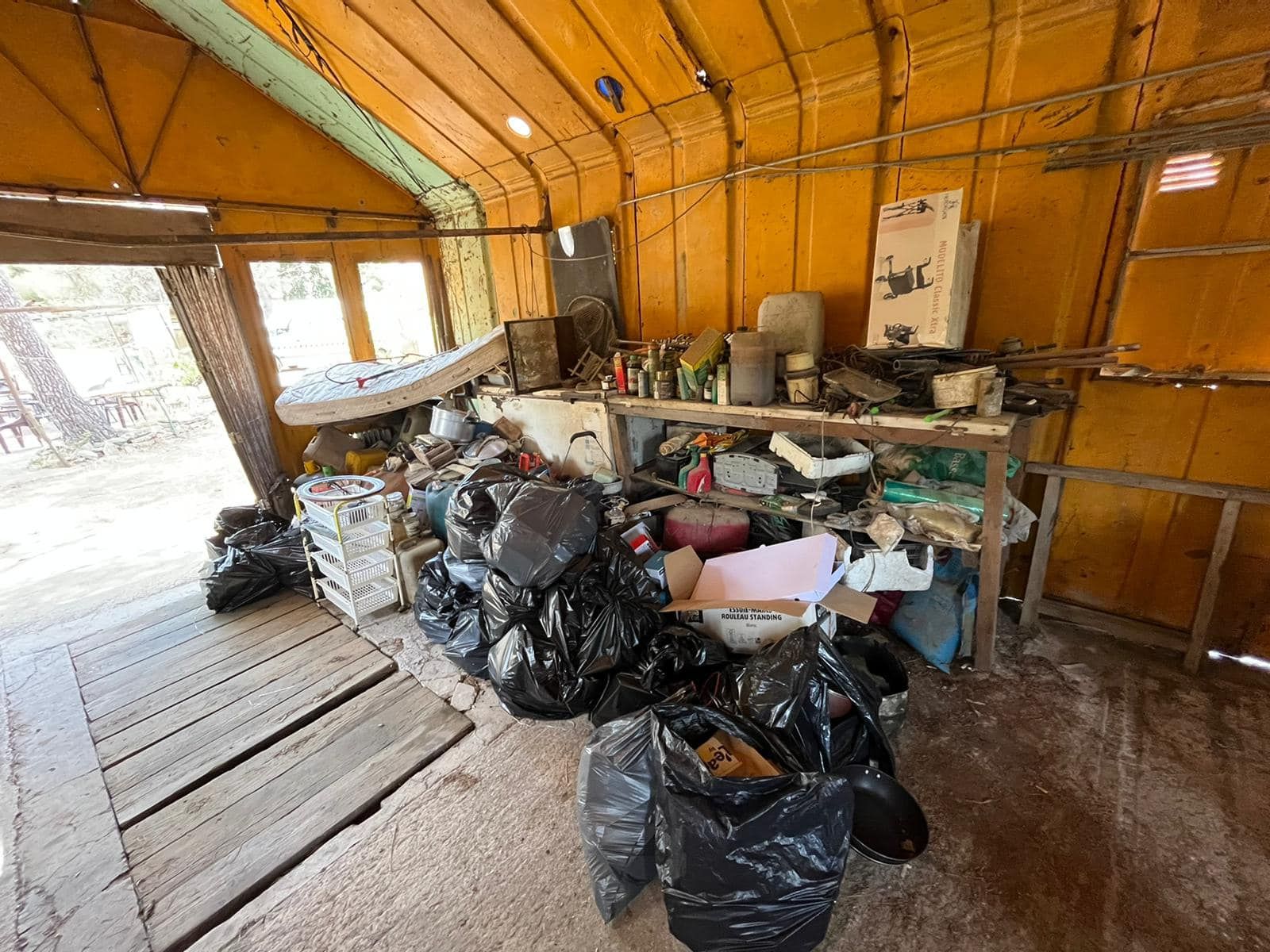 A garage filled with lots of trash bags and boxes.