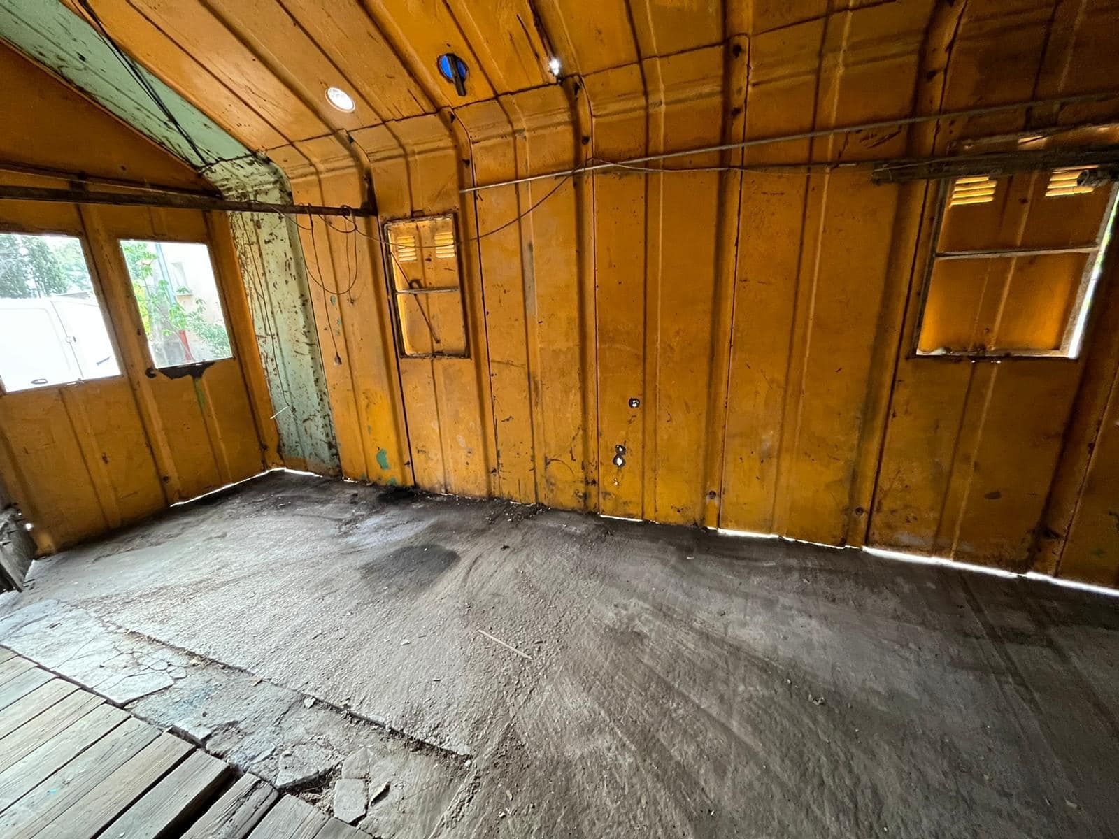An empty room with wooden walls and a concrete floor.