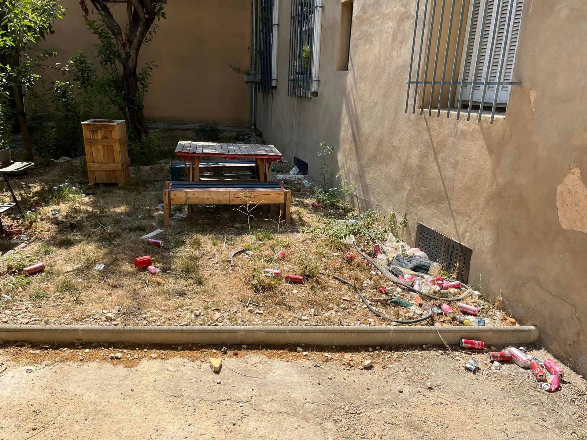 A dirty backyard with a table and chairs in it