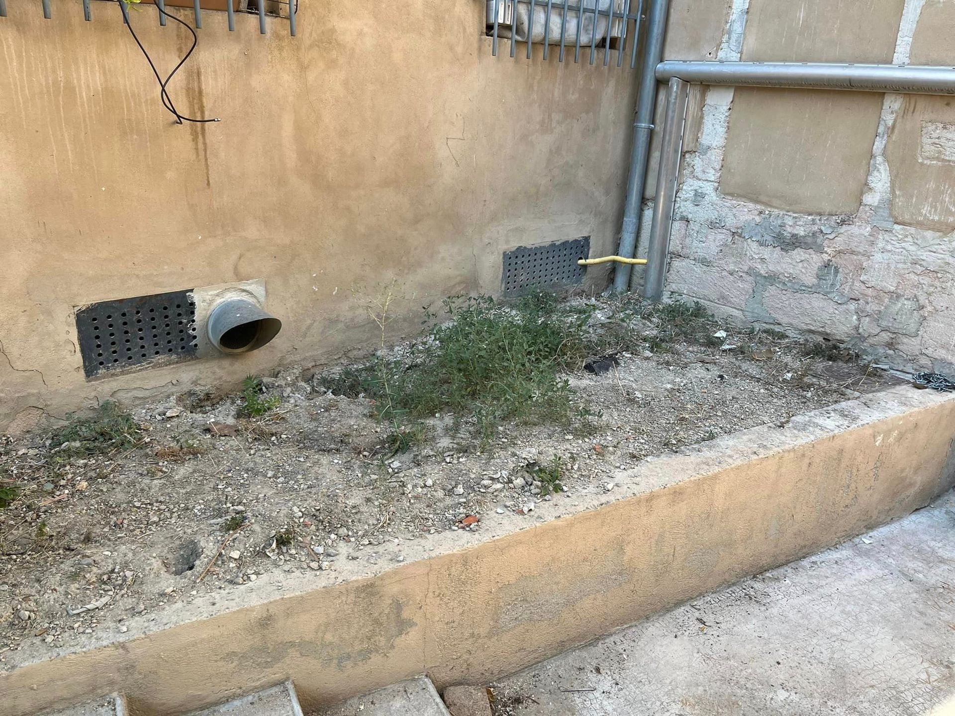 A drain pipe is coming out of the side of a building.