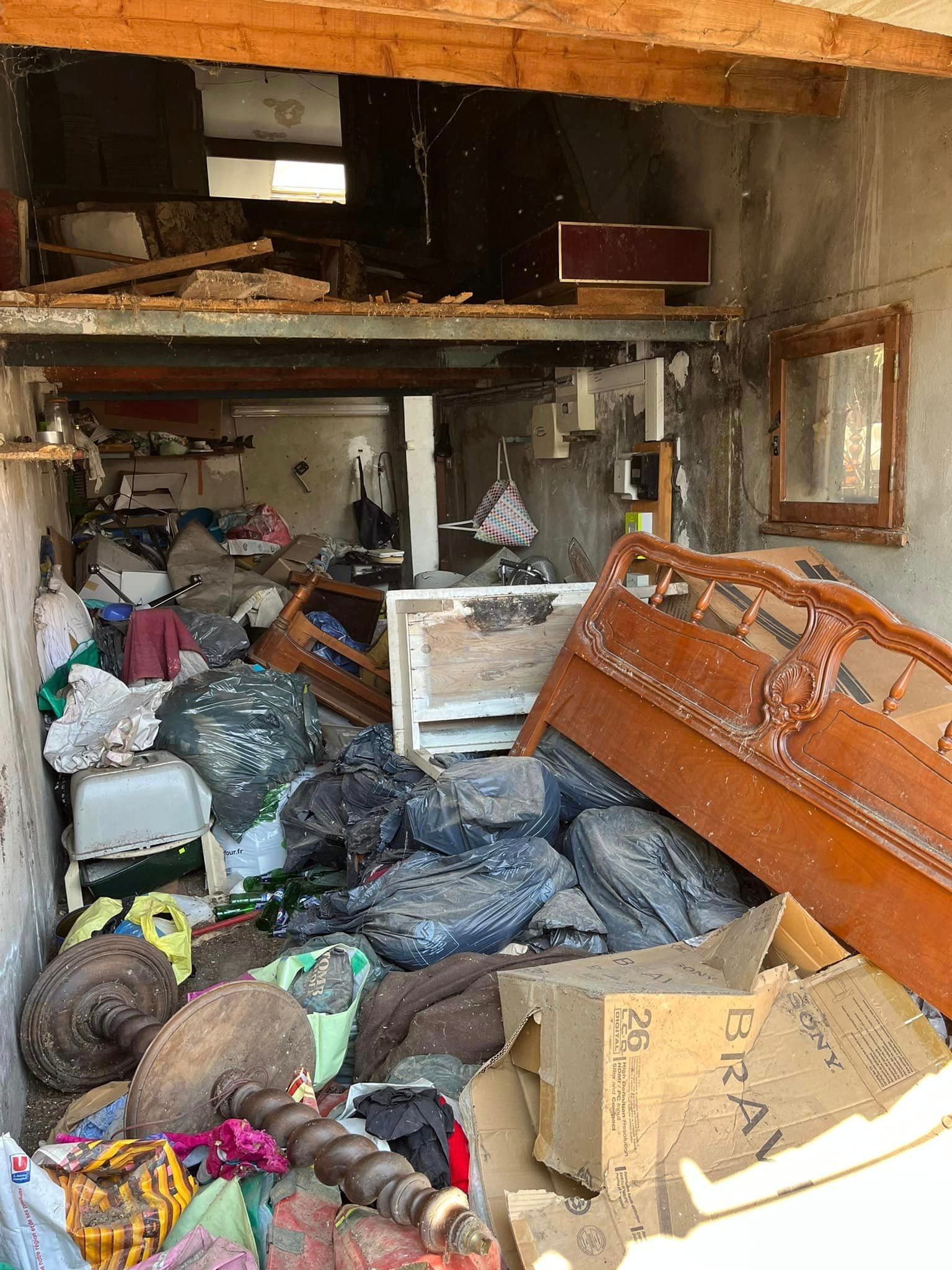 A garage filled with lots of junk and a bed.