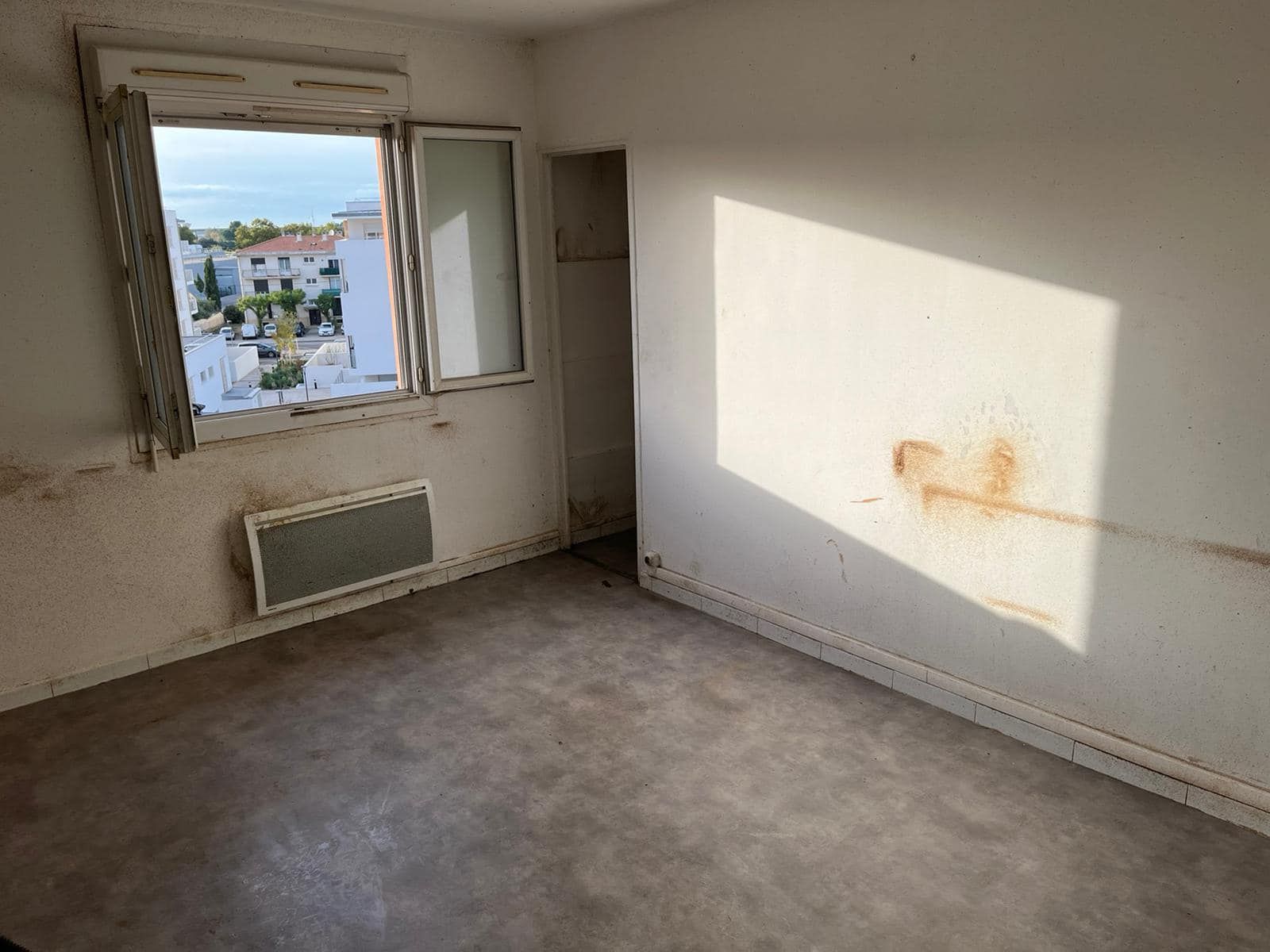 An empty room with a window and a radiator.