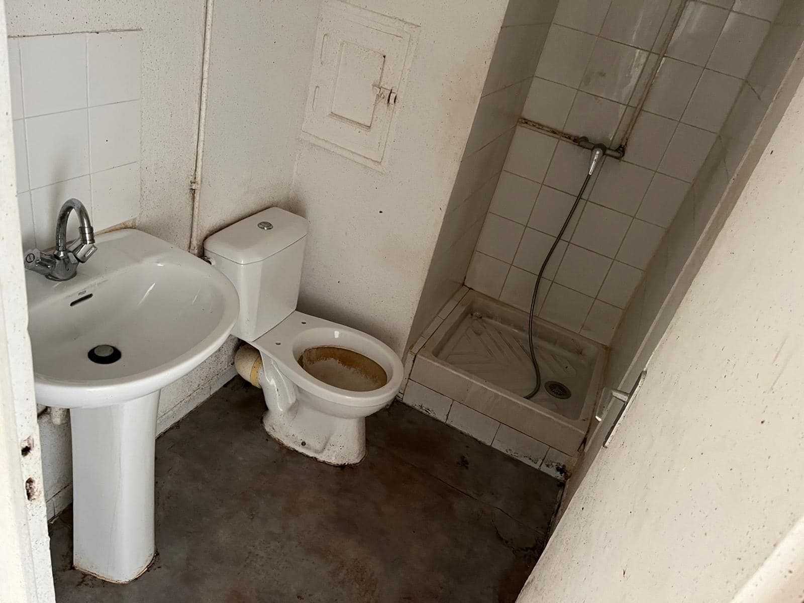 A bathroom with a toilet , sink and shower.