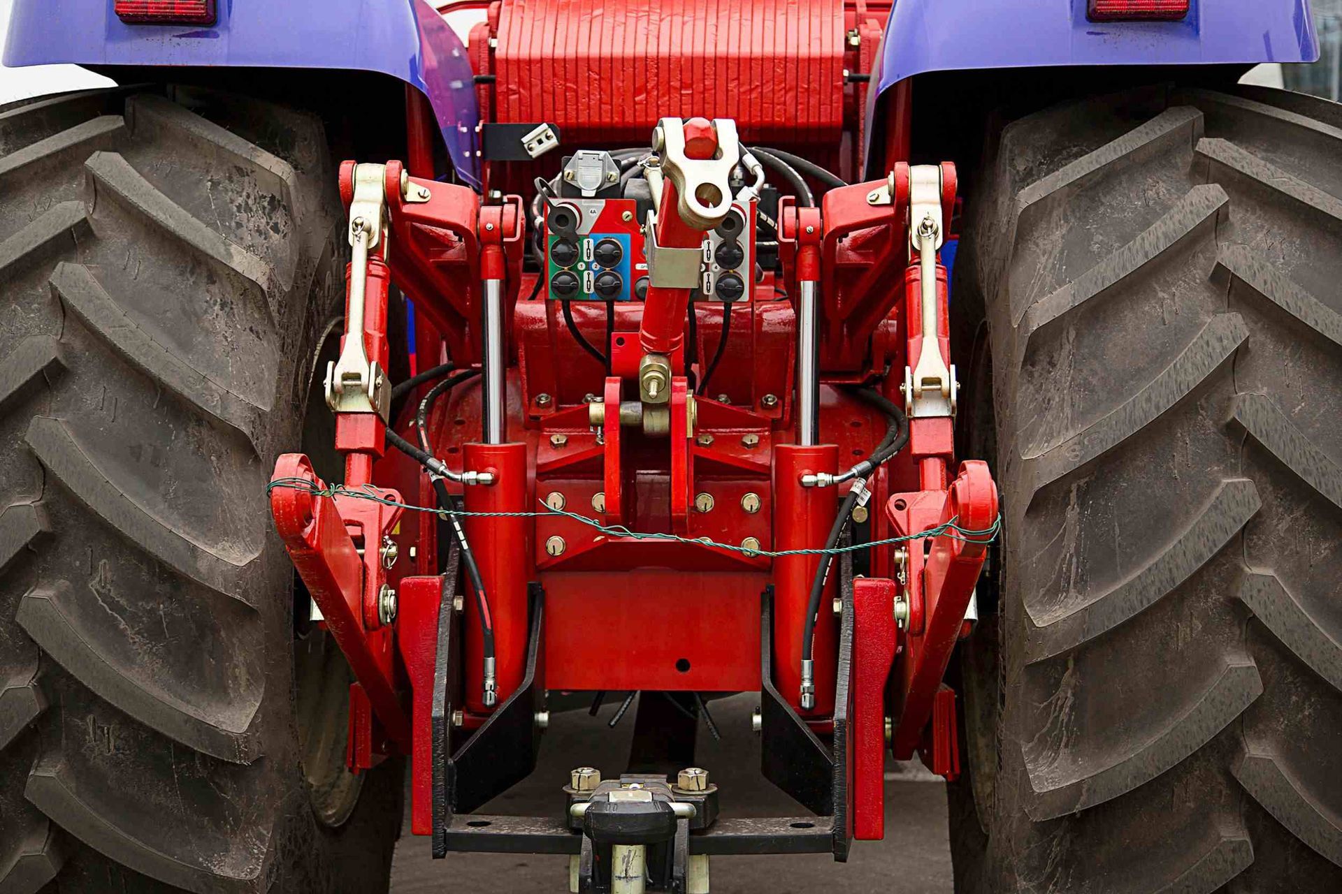 La parte trasera de un tractor rojo y morado con neumáticos grandes.