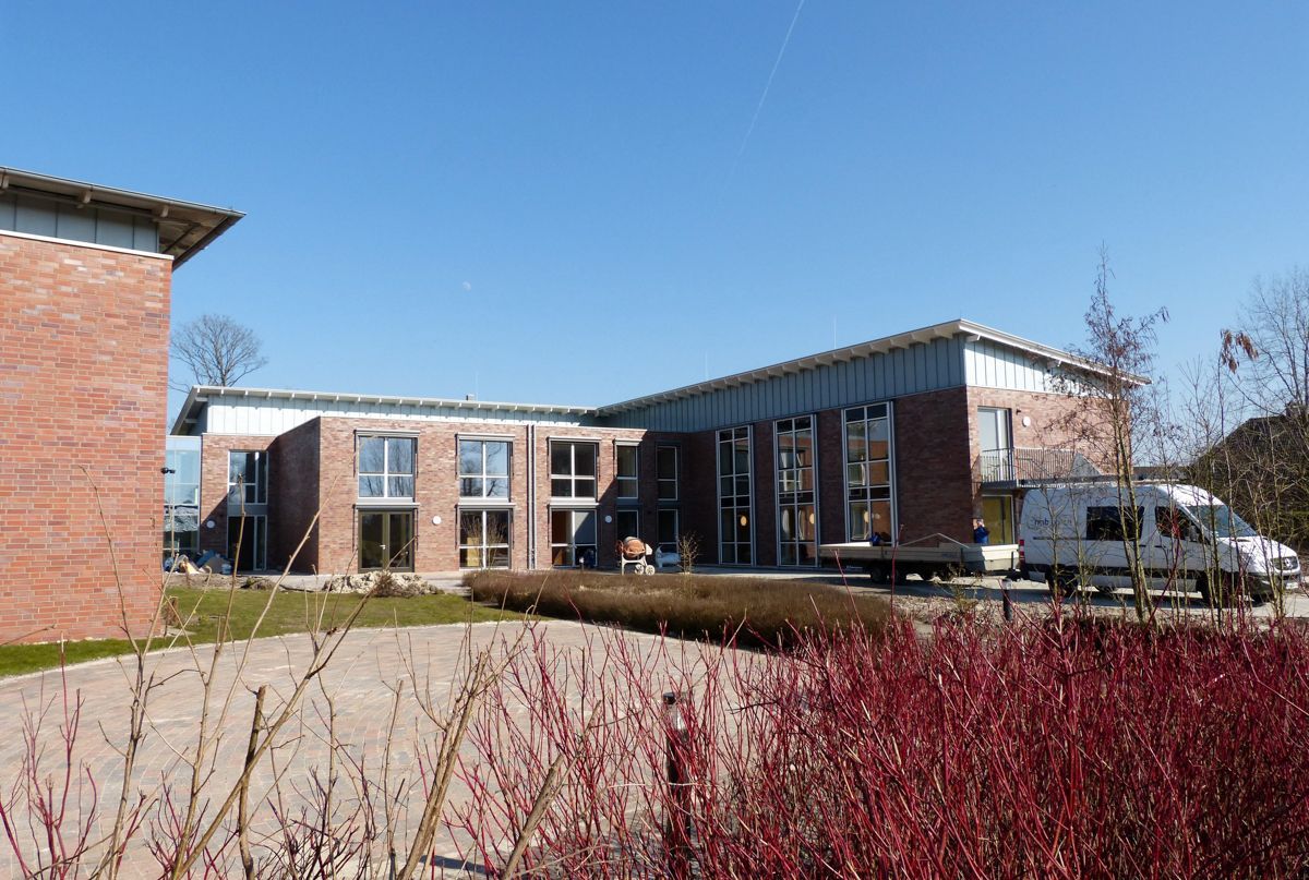 Ein großes Backsteingebäude mit vielen Fenstern und einem davor geparkten weißen Lieferwagen.