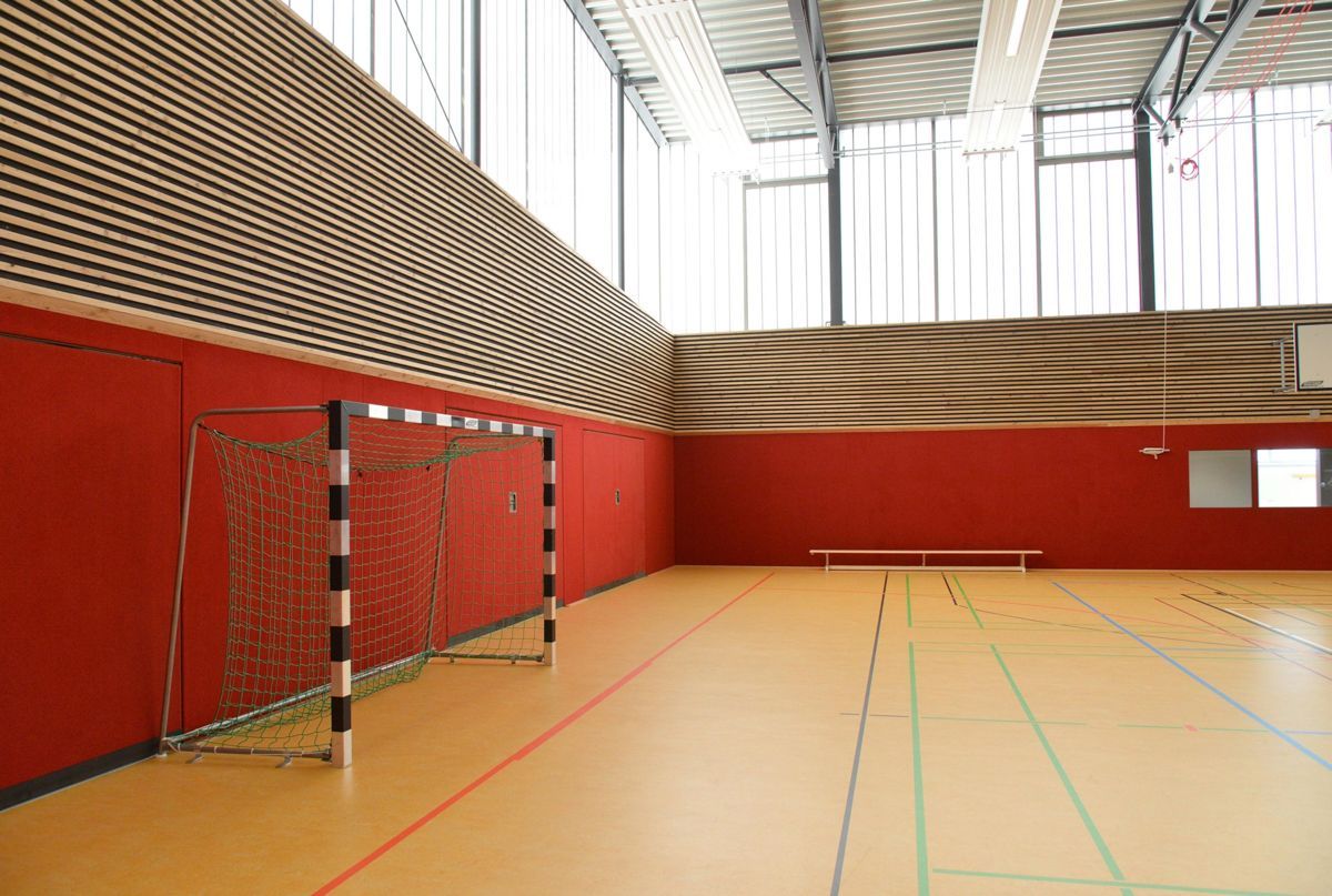 Ein leerer Basketballplatz in der Halle mit einem Korb und einer Bank.