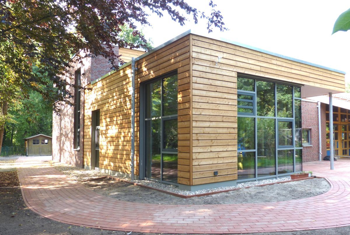 Ein Holzgebäude mit vielen Fenstern und Bäumen im Hintergrund