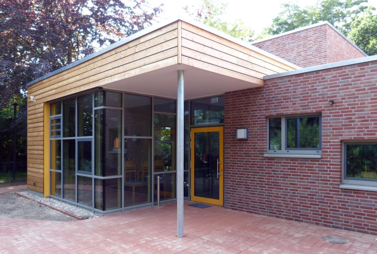 Ein Backsteingebäude mit einem Holzdach und einer gelben Tür