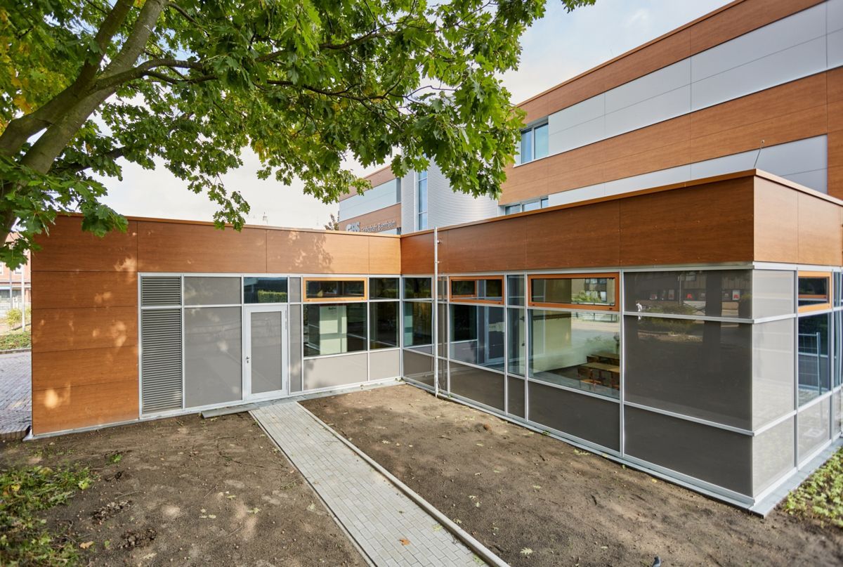 Ein Gebäude mit vielen Fenstern und einem Baum davor