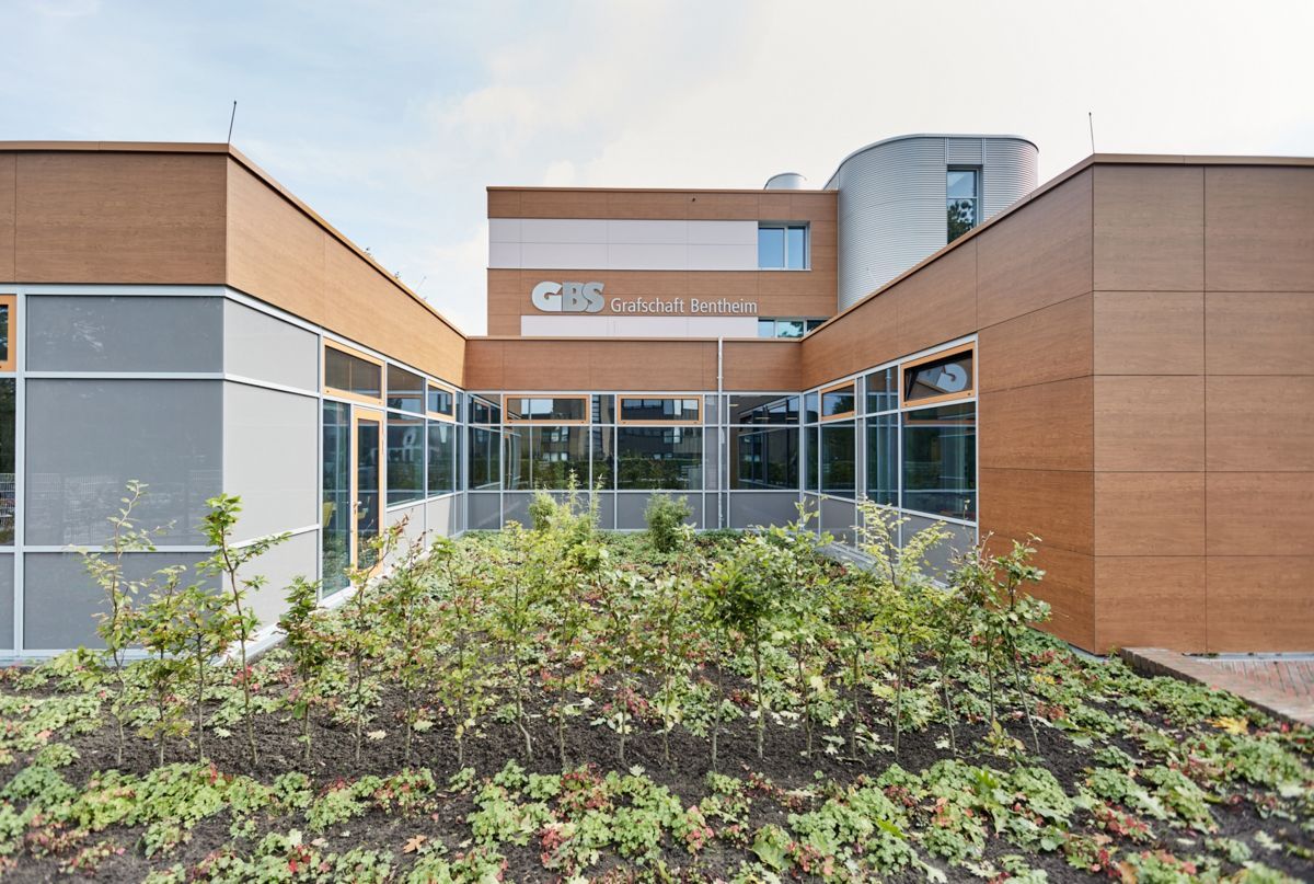 Ein großes Gebäude mit vielen Fenstern und Bäumen davor.