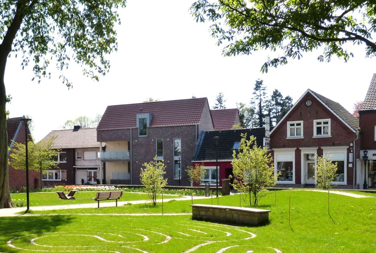 Vor einer Häuserreihe ist ein Labyrinth ins Gras gezeichnet