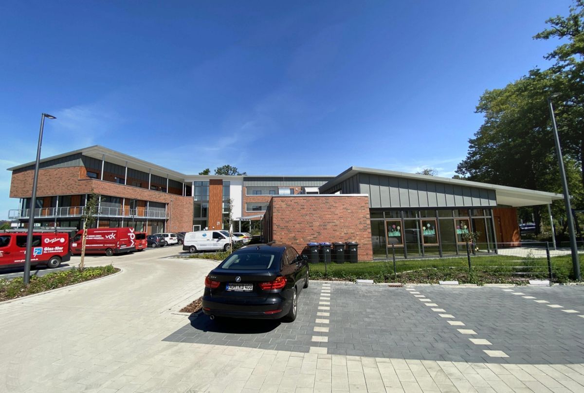 Vor einem großen Gebäude parkt ein schwarzes Auto.