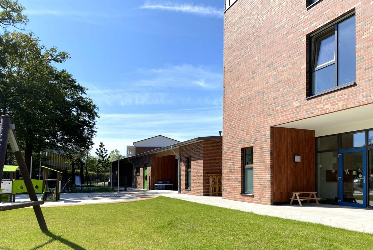 Ein großes Backsteingebäude mit einer großen Rasenfläche davor.