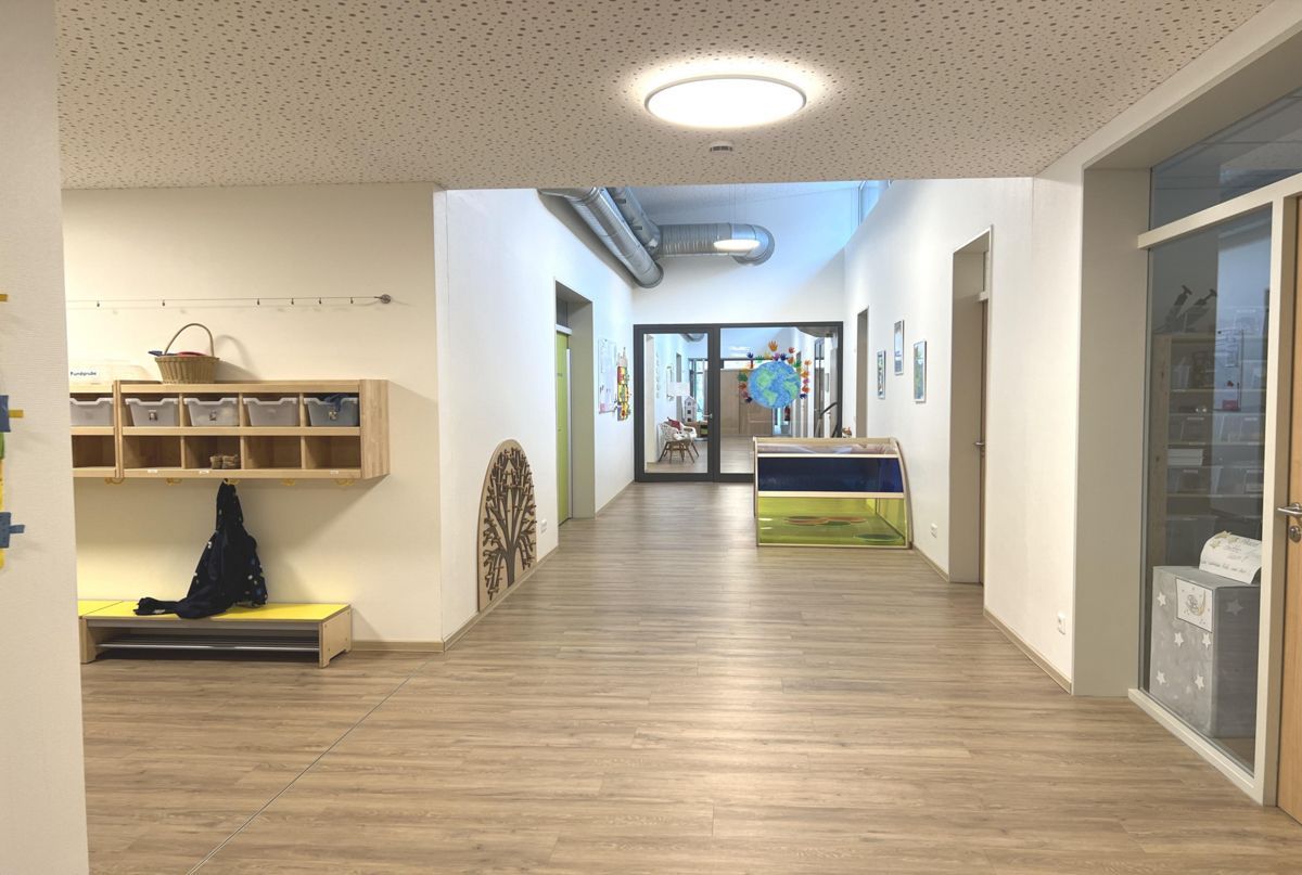 Ein Flur mit Holzboden und weißen Wänden in einem Gebäude.