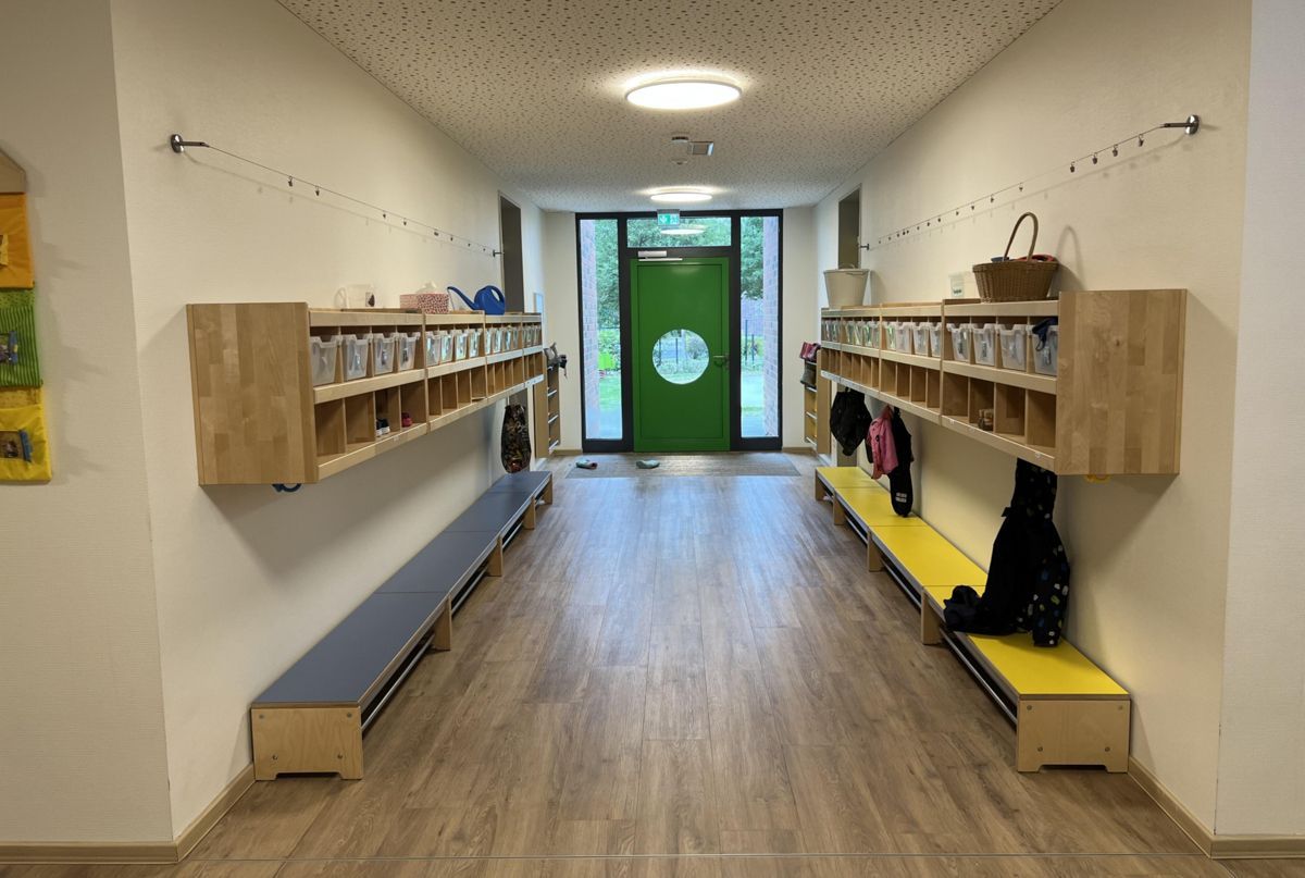 Ein Flur mit einer grünen Tür und Holzbänken