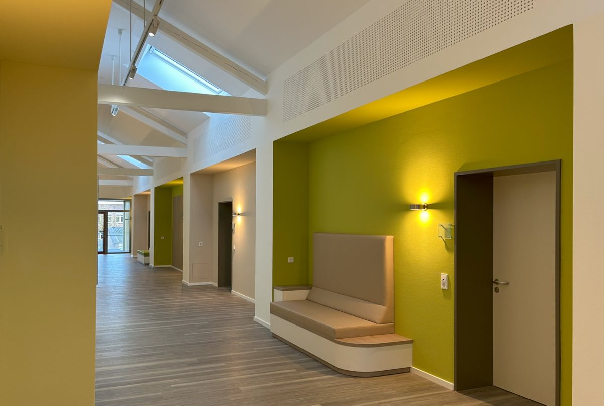 Ein langer Flur mit grünen Wänden und einer Bank in der Mitte.