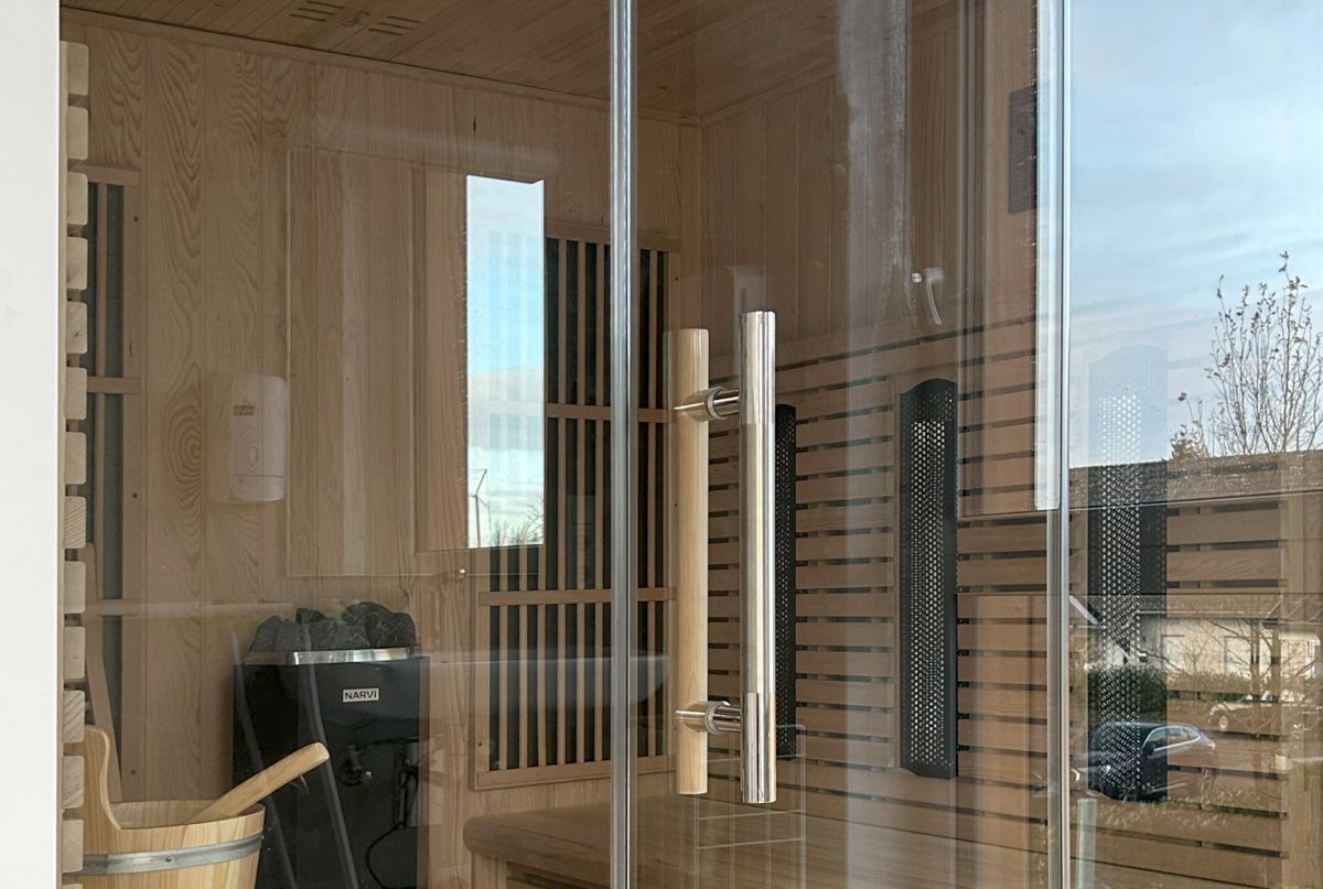 Eine Holzsauna mit Glastür und Holzeimer.