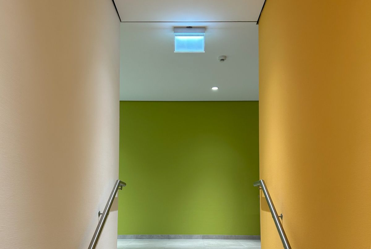 Ein Flur mit gelben und grünen Wänden und einem blauen Licht an der Decke