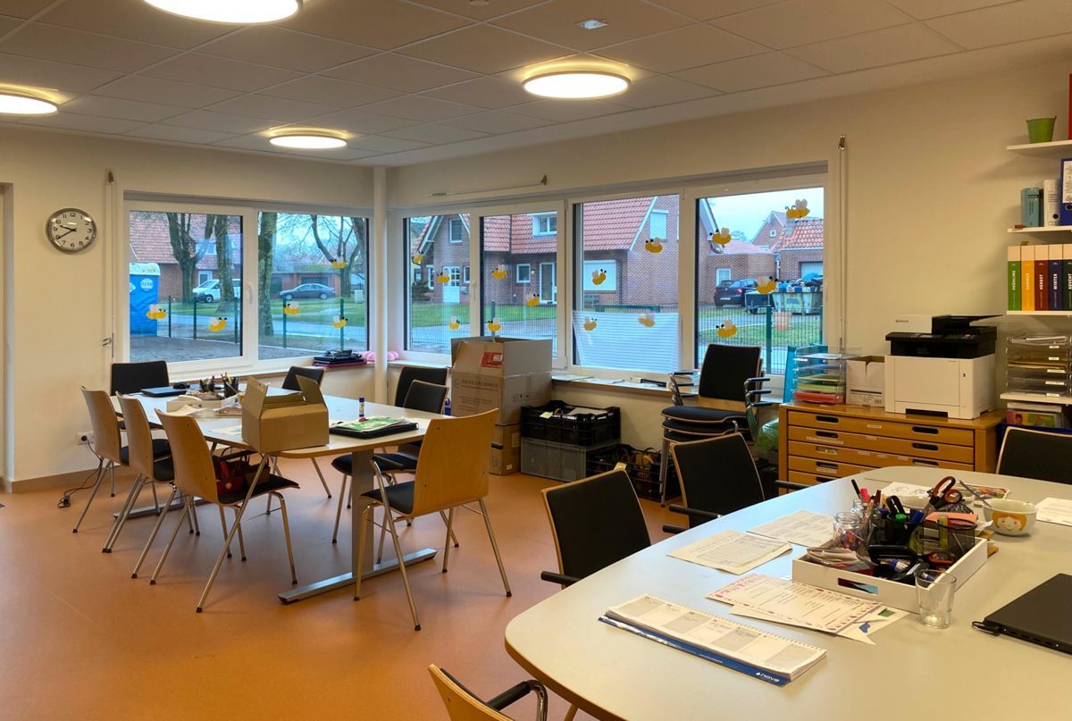 Ein Raum mit Tischen und Stühlen und einer Uhr an der Wand.