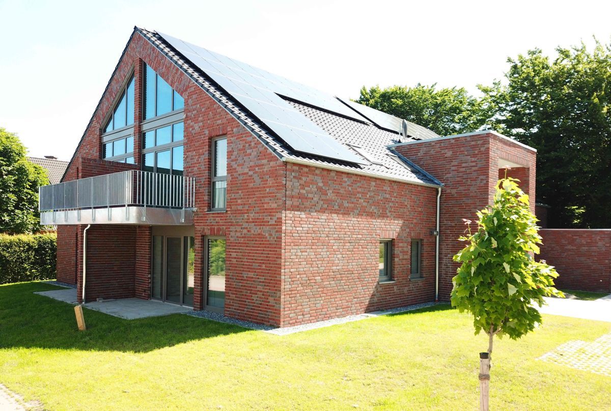 Ein großes Backsteinhaus mit Balkon und Solarzellen auf dem Dach.