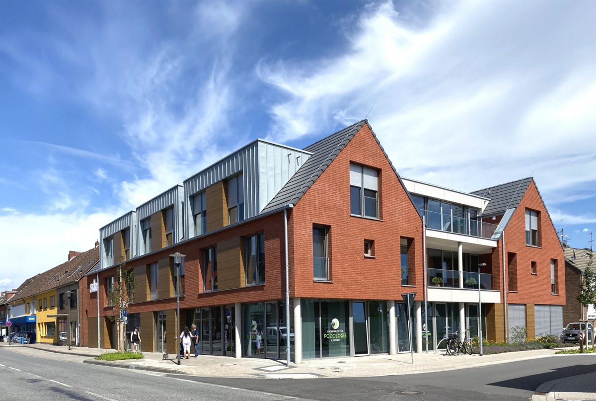 An einer Straßenecke steht ein großes rotes Gebäude mit vielen Fenstern.