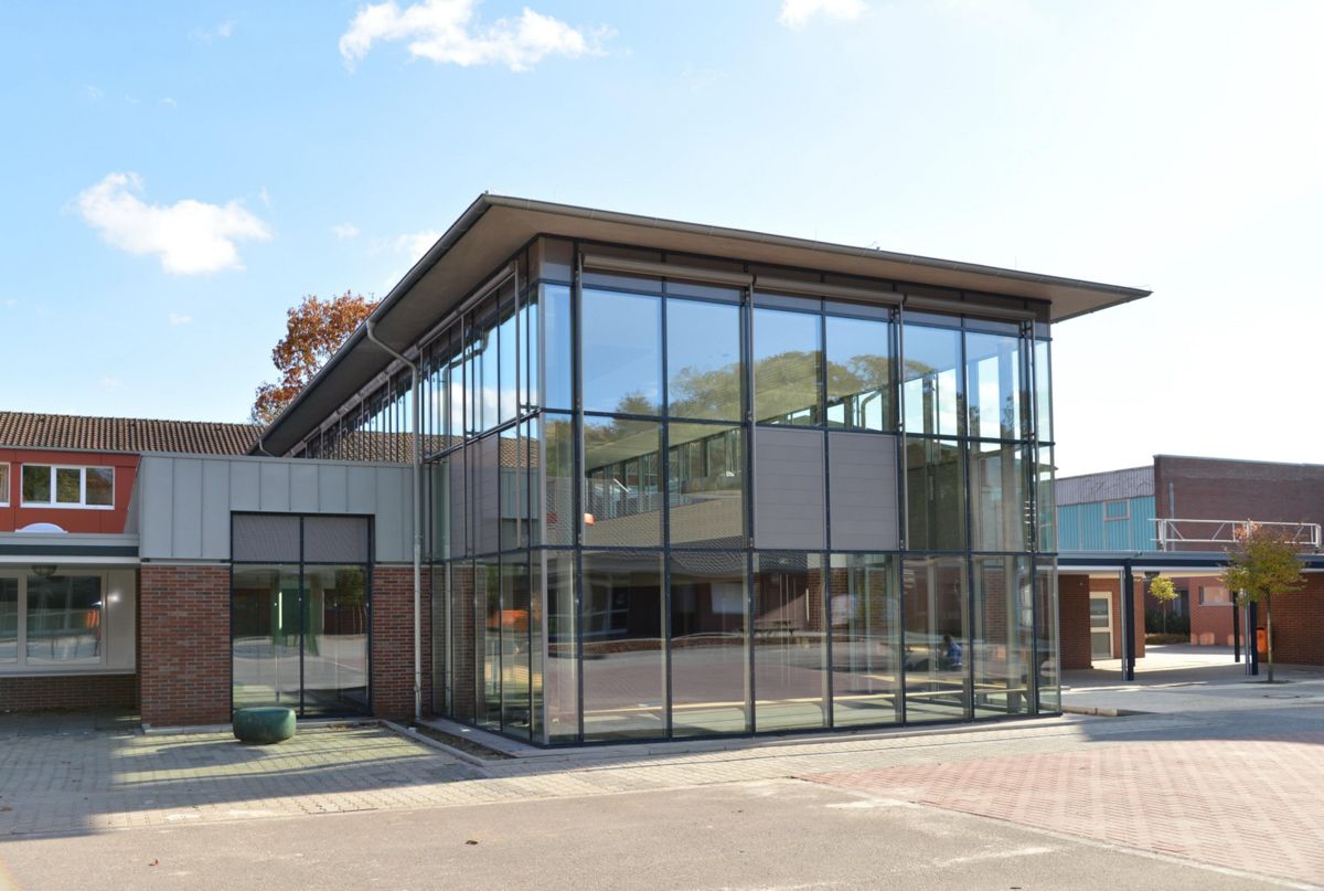 Ein großes Gebäude mit vielen Fenstern und einem Backsteingebäude im Hintergrund