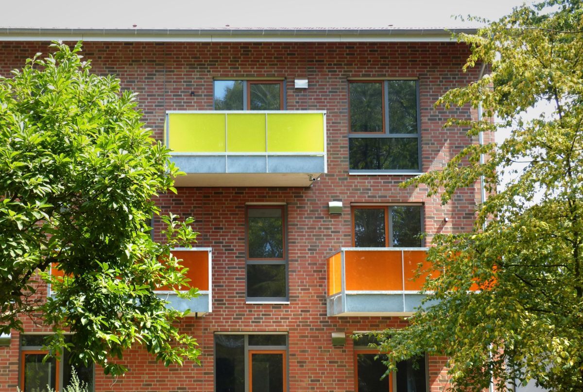 Ein Backsteingebäude mit einem gelben Balkon und orangefarbenen Balkonen