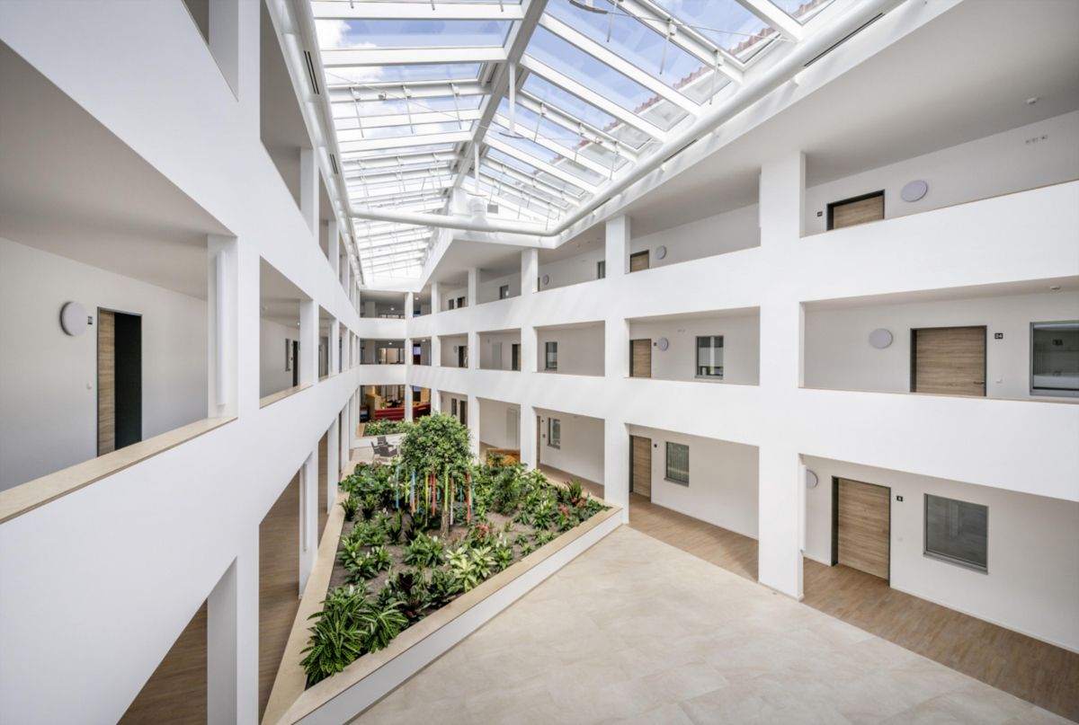 Ein großes Gebäude mit einem üppigen grünen Garten in der Mitte.