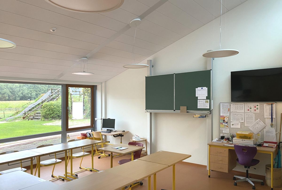 Ein Klassenzimmer mit Tischen und Stühlen und einer grünen Tafel