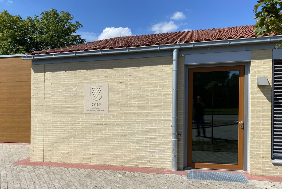 Ein Backsteingebäude mit einer Holztür und einem Schild an der Seite.