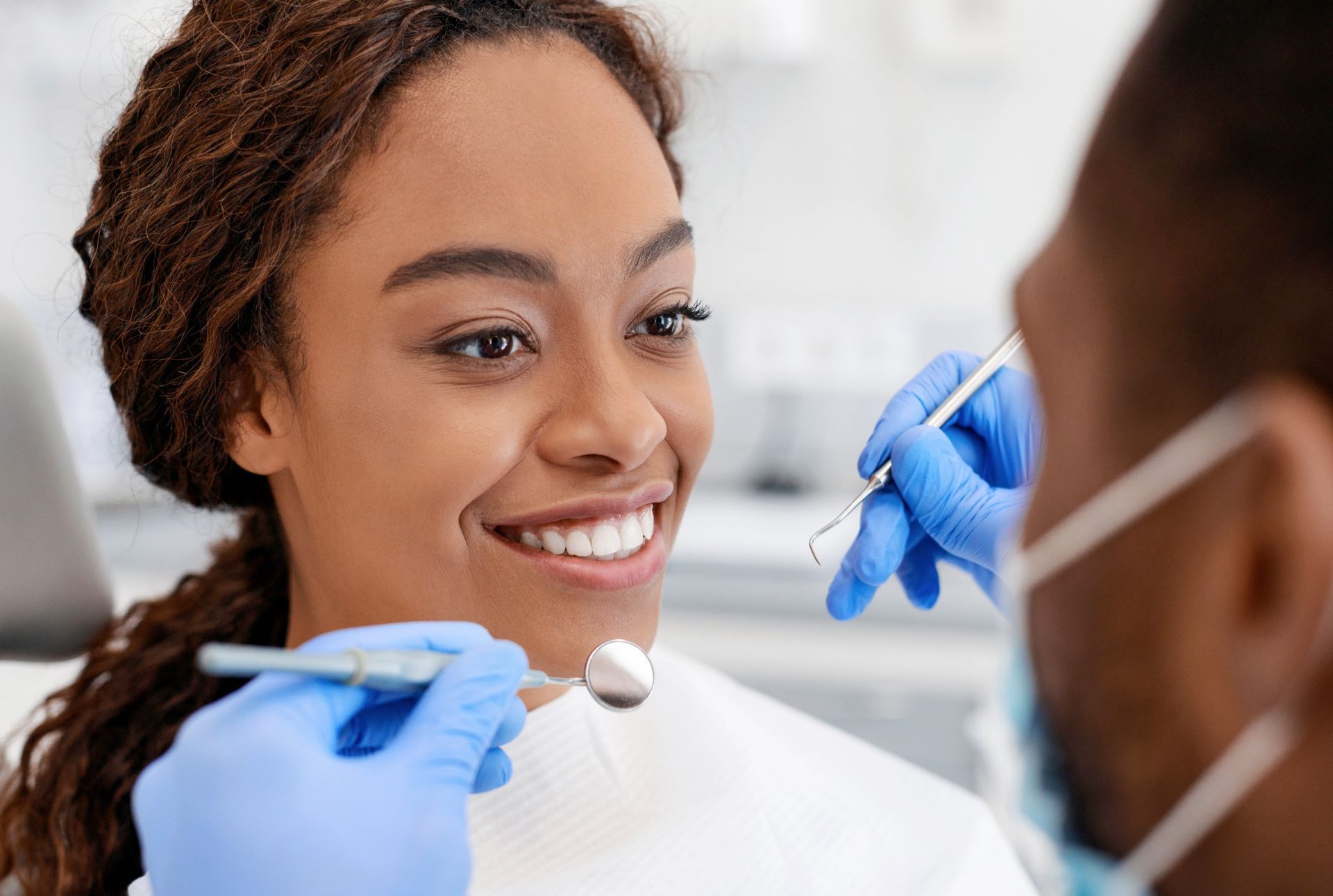 Una mujer sonríe mientras un dentista le examina los dientes.