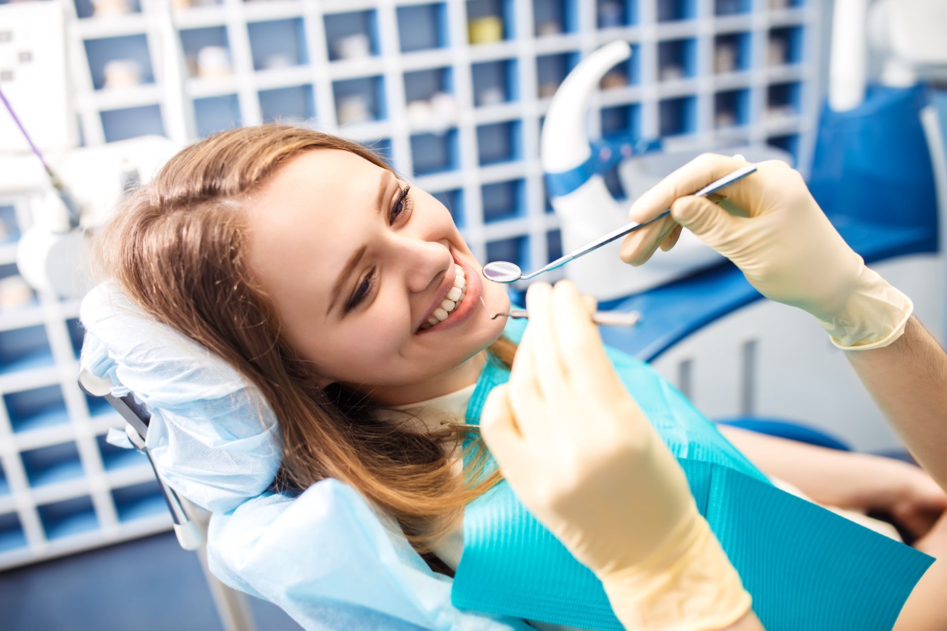 Una mujer está sentada en una silla dental mientras un dentista le examina los dientes.