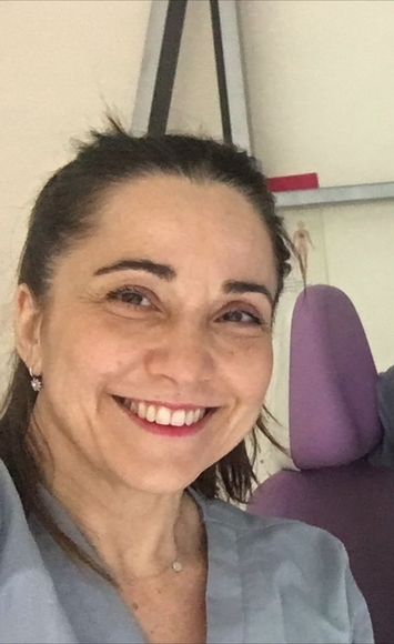 Una mujer con una bata de laboratorio está sonriendo en un laboratorio.