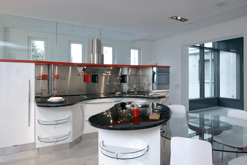 Eine Küche mit weissen Schränken und schwarzen Arbeitsplatten. Foto von Sandro Luisi Küchenbau