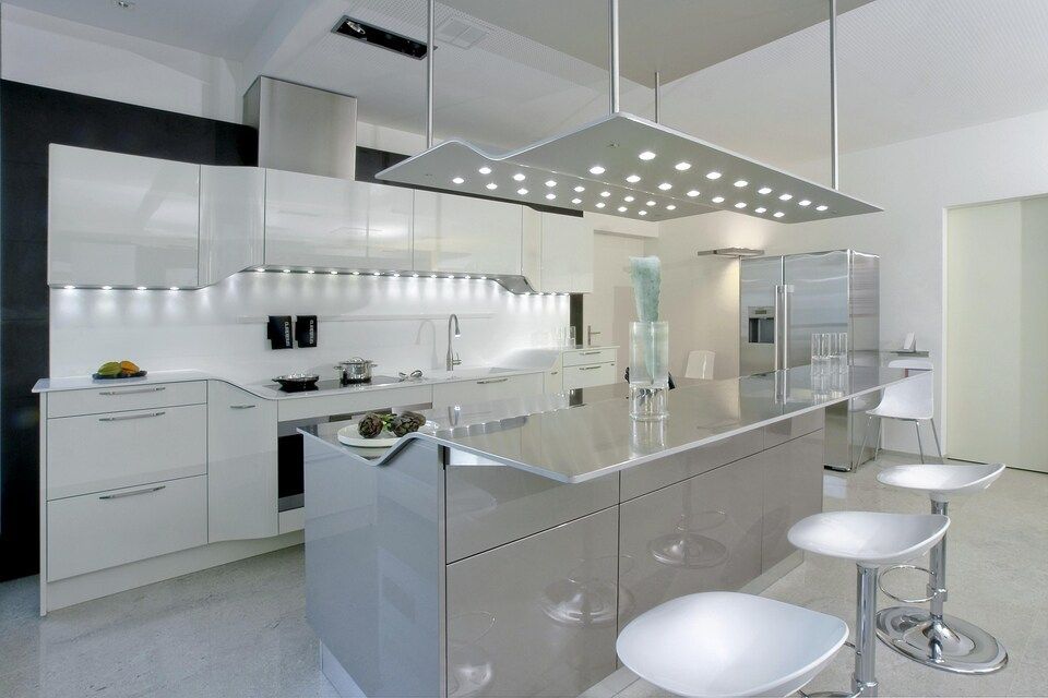Eine moderne Küche mit weissen Schränken und Hockern. Foto von Sandro Luisi Küchenbau