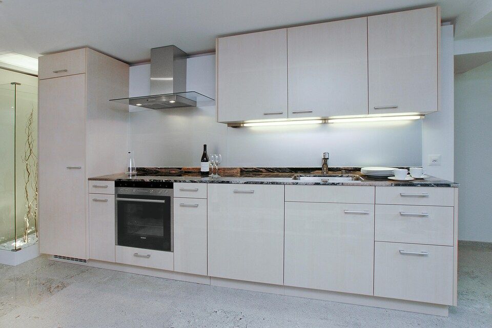 Eine Küche mit weissen Schränken und Geräten aus Edelstahl. Foto von Sandro Luisi Küchenbau