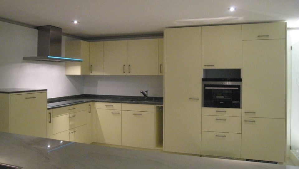 Eine Küche mit weissen Schränken und schwarzen Arbeitsplatten. Foto von Sandro Luisi Küchenbau