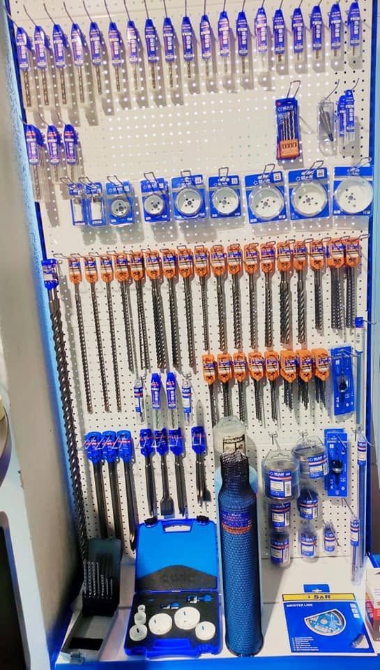 Présentation d'articles de pêche variés (cannes, moulinets, leurres et accessoires) disposés sur un mur et une étagère.