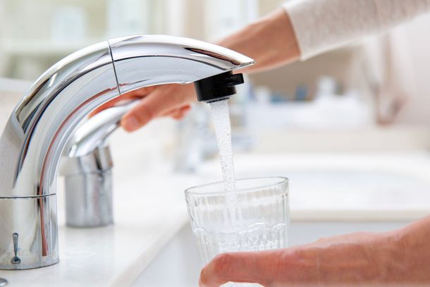 Le remplissage d'un verre transparent d'eau provenant d'un robinet de cuisine chromé.