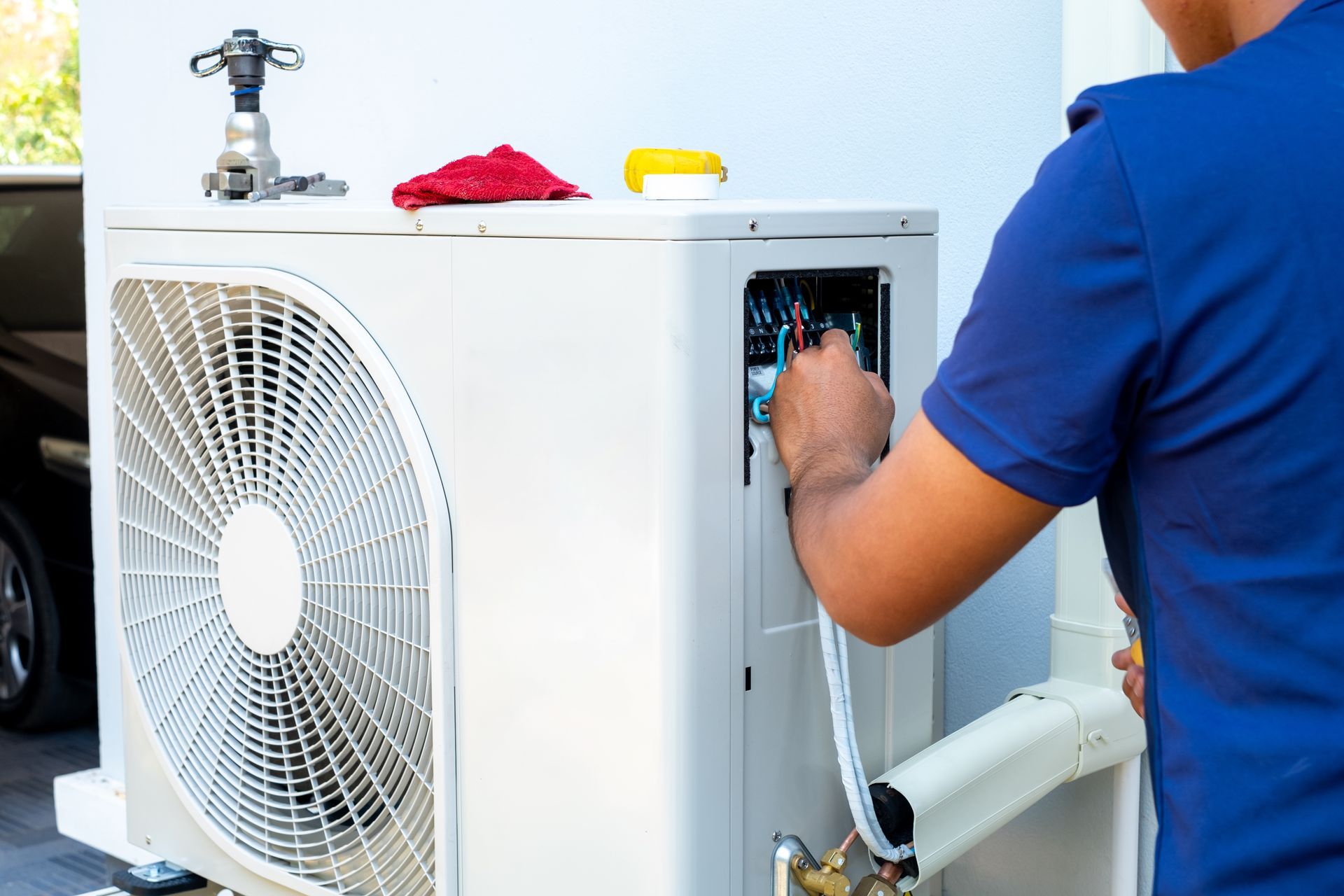 Un technicien effectue l'entretien d'un climatiseur extérieur avec des outils par une journée ensoleillée.