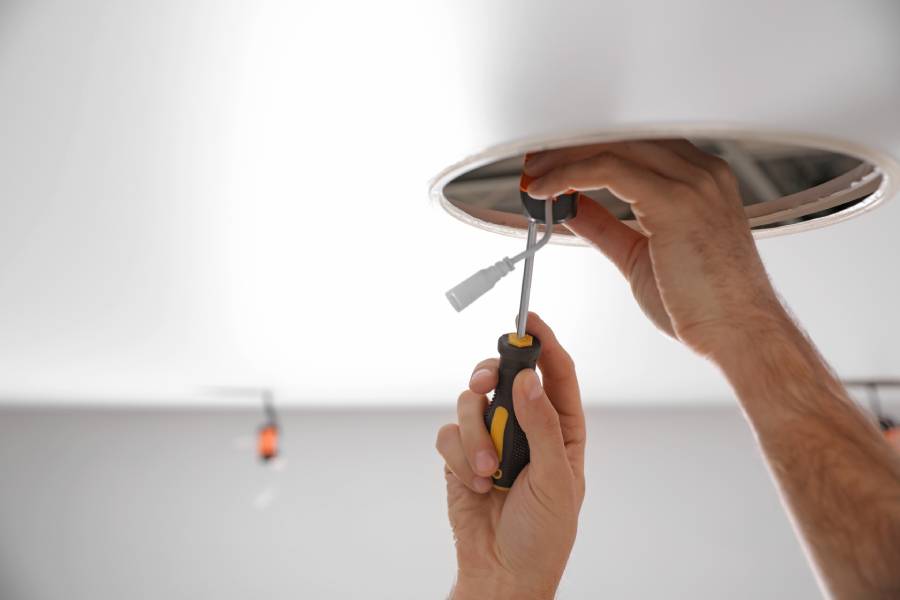 Zwei Hände welche an der Decke die Elektroinstallation versorgen