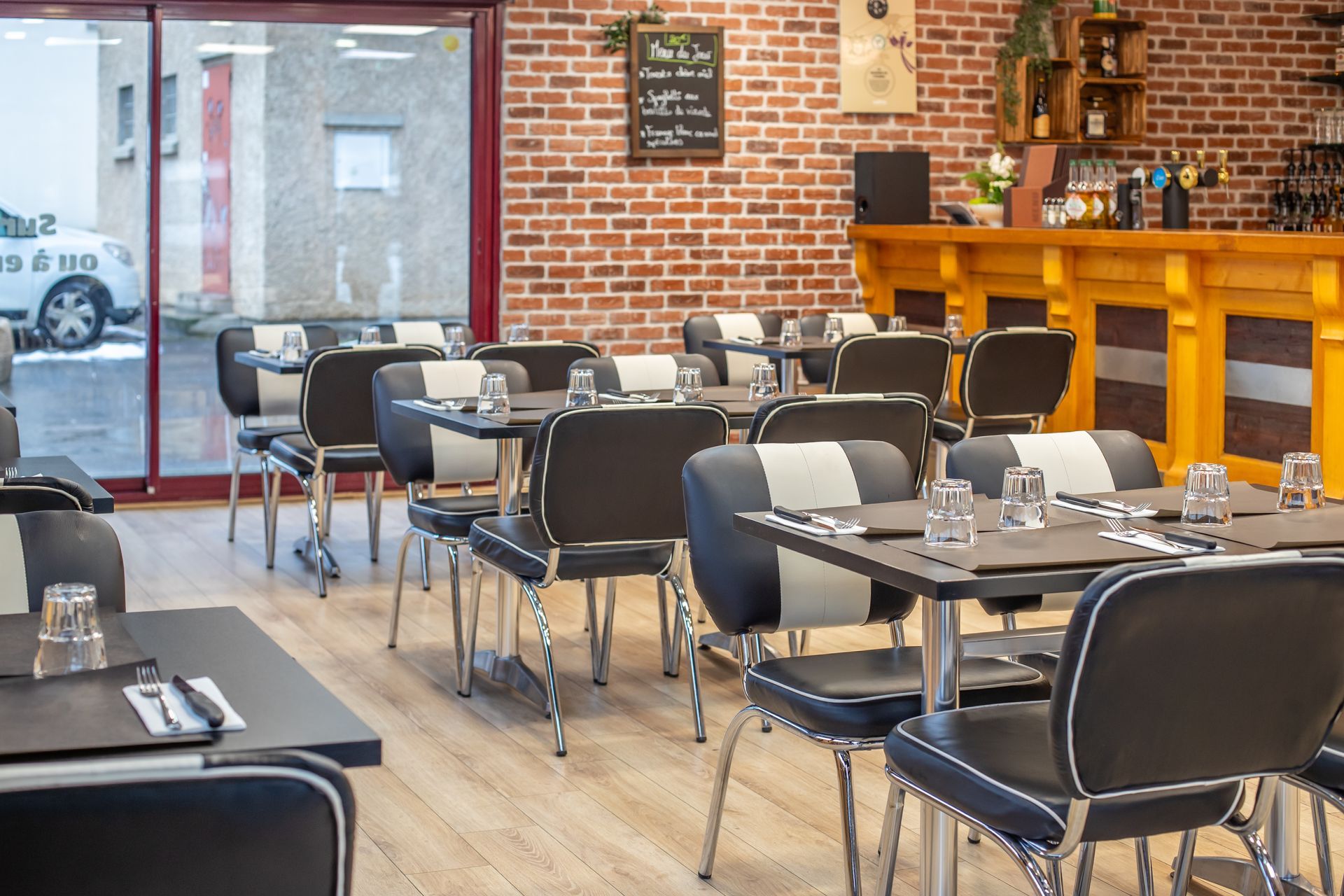 Intérieur d'un restaurant avec vue sur les montagnes enneigées. Tables et chaises au premier plan.