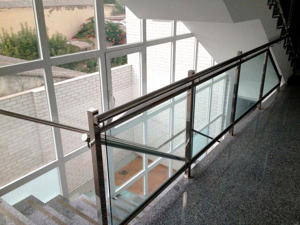 Una escalera con barandilla de cristal y muchas ventanas.