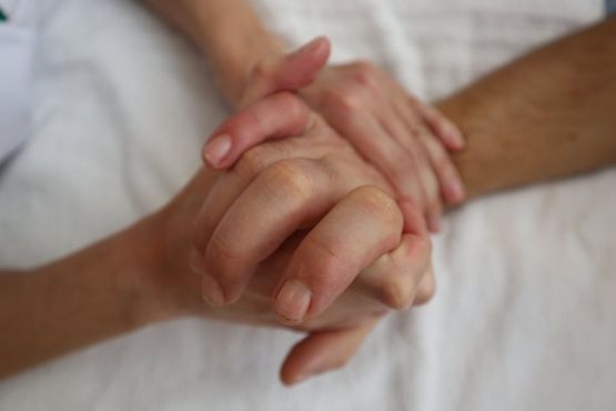Una persona sostiene la mano de otra persona en una cama.