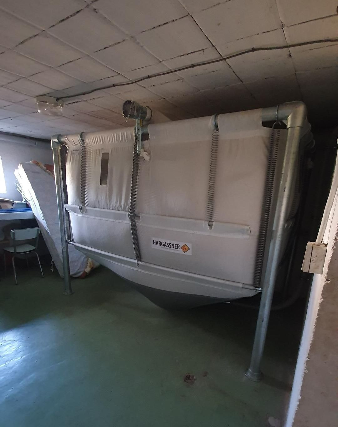 Grand silo à granulé. Structure métallique et chaînes visibles.