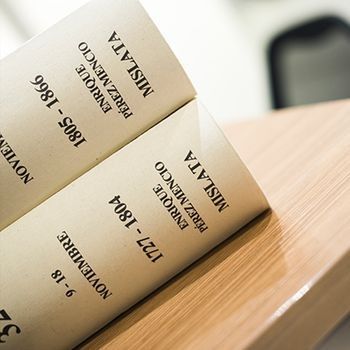Libro abierto con páginas beige que muestran texto y fechas en negro sobre una superficie de madera.